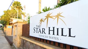 A sign for "The Star Hill" with a logo of three stars and text indicating it offers serviced suites. - The Star Hill Hotel (Balikpapan)