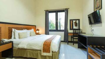 A hotel room with a bed, a desk, a chair, a television, and a window.