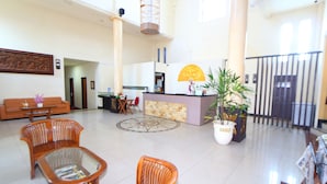 A spacious lobby with a reception desk, a large potted plant, and several wicker chairs. - The Star Hill Hotel (Balikpapan)