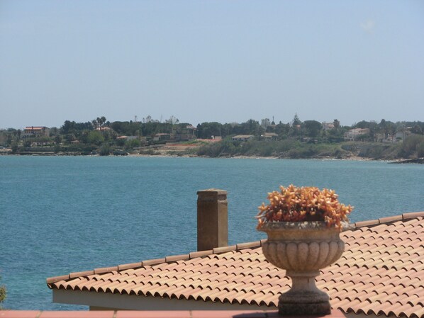 A view of a coastal area with a tiled roof and a decorative urn in the foreground. - B&B Le Saline (Syracuse)