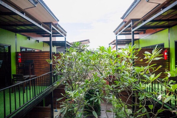Un pasillo con una valla de madera, una escalera y un árbol en el centro.