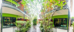 Un pasillo con paredes de vidrio, un banco de madera y plantas.