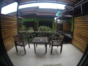 A covered outdoor seating area with wooden furniture and green plants. - Leelawadee Lipe Resort (Koh Lipe)
