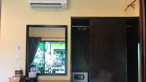 A room with a wooden table, a small kitchen area with a microwave, a window with a view of the outside, and a door with a handle. - Leelawadee Lipe Resort (Koh Lipe)