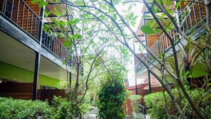 A courtyard with a central pathway surrounded by lush greenery and wooden balconies. - Leelawadee Lipe Resort (Koh Lipe)