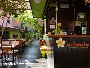 A reception area with a wooden counter, a clock, and a sign indicating check-out time. - Leelawadee Lipe Resort (Koh Lipe)