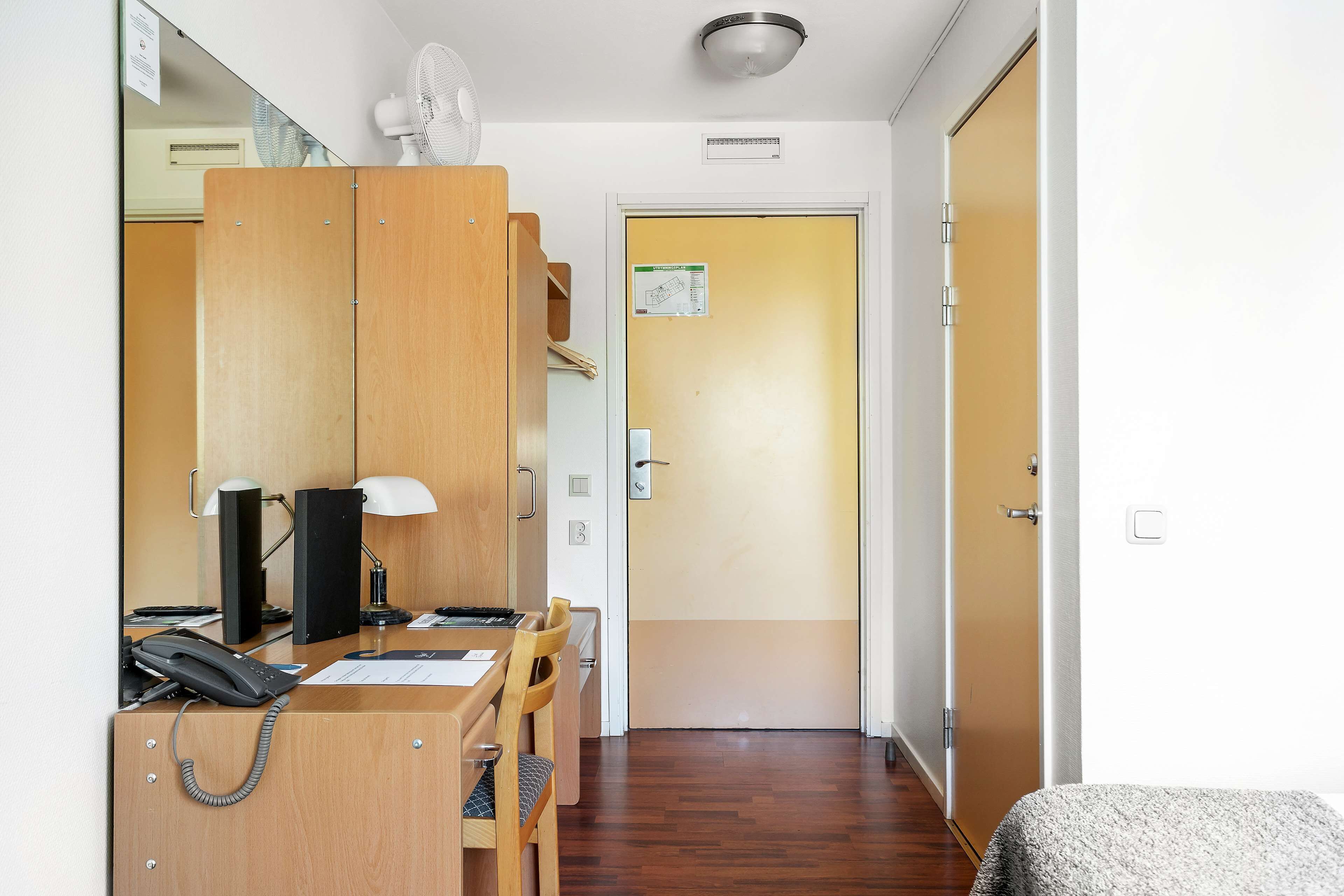 Une chambre d’hôtel avec un bureau en bois, un téléphone, une lampe et un lit.