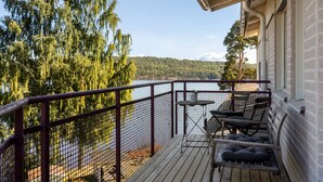 Eine Holzterrasse mit Metallgeländer, das auf einen See mit umliegenden Bäumen blickt.