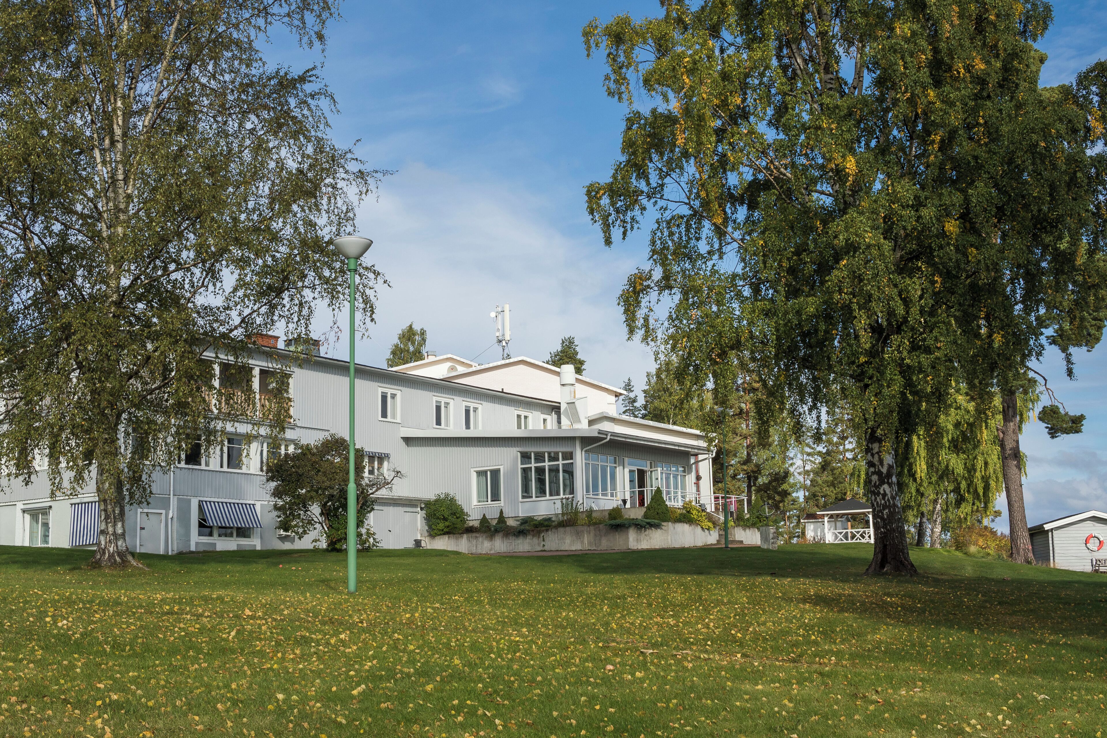 A two-story building with a flat roof, large windows, and a visible satellite dish.