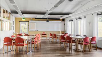 A conference room with wooden tables and red chairs, a whiteboard, and large windows.