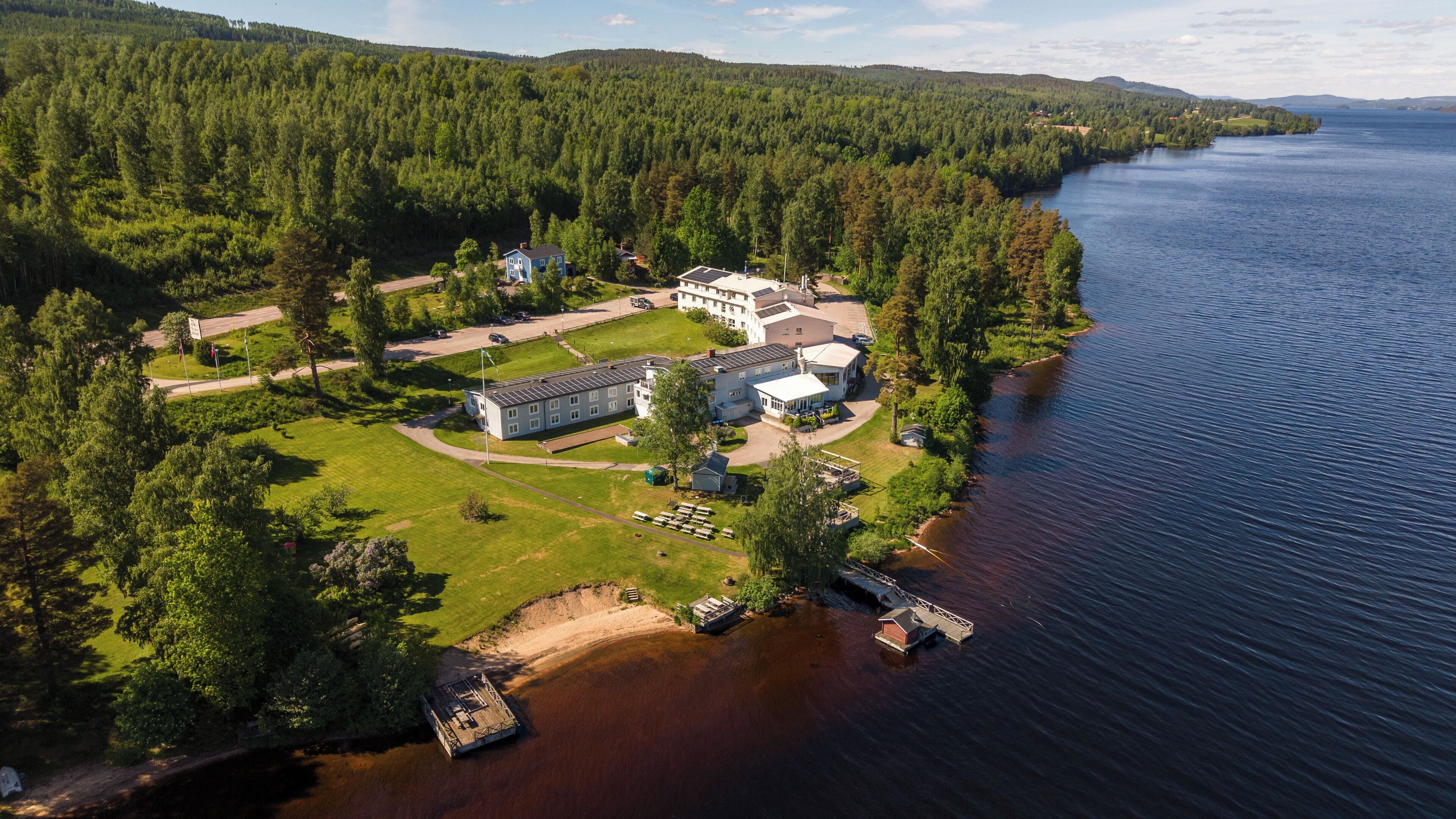 Une propriété située au bord d’un lac, comprenant plusieurs bâtiments, un quai et une zone boisée.