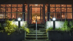 Ein Gebäudeeingang mit einer Treppe, die zu einem beleuchteten Innenraum führt.