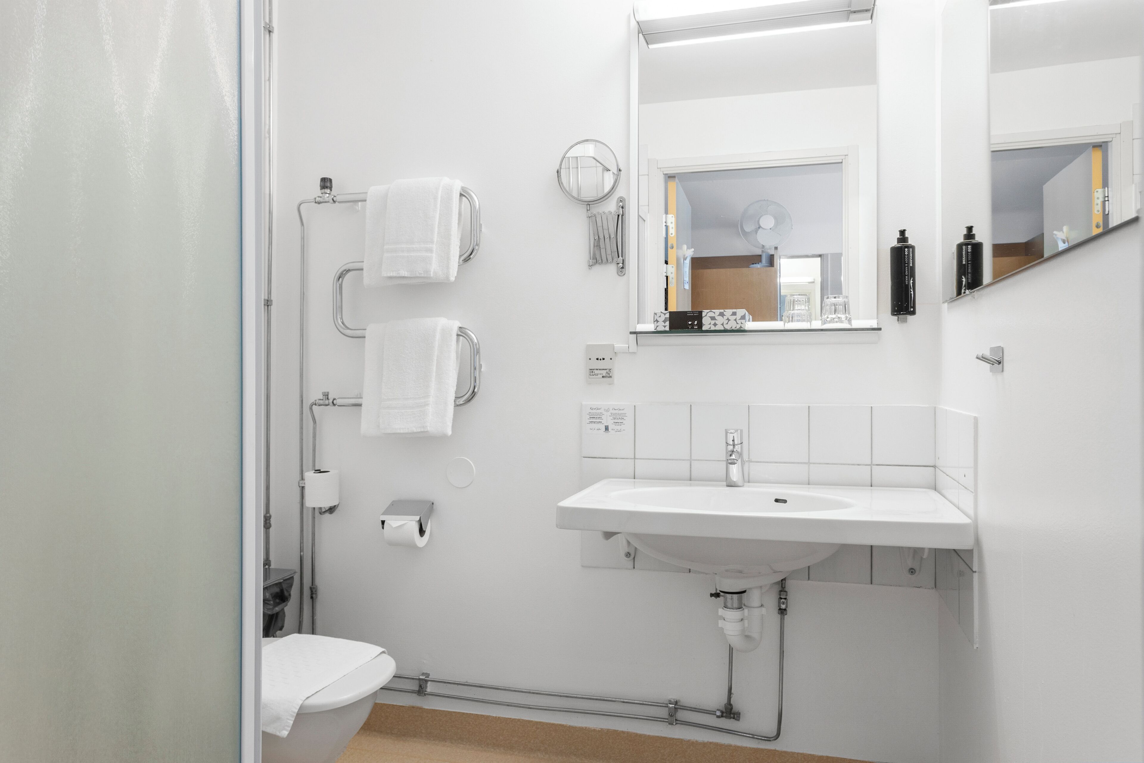 A modern bathroom with a white sink, mirror, and toilet.