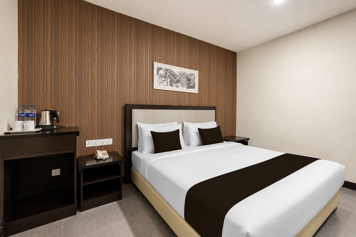 Une chambre d’hôtel équipée d’un lit, de tables de chevet, d’une machine à café et d’un téléphone.