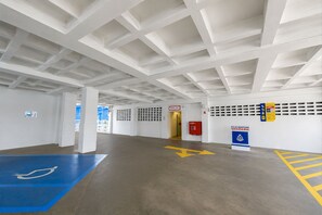 Un vaste espace de stationnement intérieur, doté de flèches directionnelles bien visibles, d’une place de stationnement bleue réservée aux personnes handicapées et d’une sortie de secours clairement indiquée.