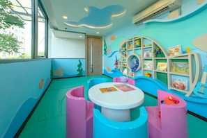 A children's play area with a slide, a table, and shelves with toys and books.