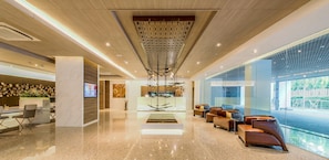 A modern lobby with a reception desk, seating area, and a large window offering a view of the outdoors.