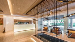 A modern lobby with a reception desk, seating area, and a water feature. - Qiss Residence by Bliston (Bangkok)