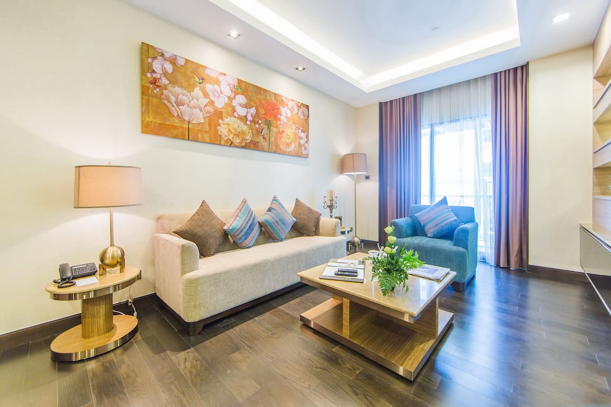 Un salon moderne avec un canapé, une table basse et un fauteuil bleu. Un tableau est accroché au mur et une lampe se trouve sur une table d’appoint.