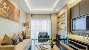 A modern living room with a sofa, a coffee table, and a TV. - Qiss Residence by Bliston (Bangkok)