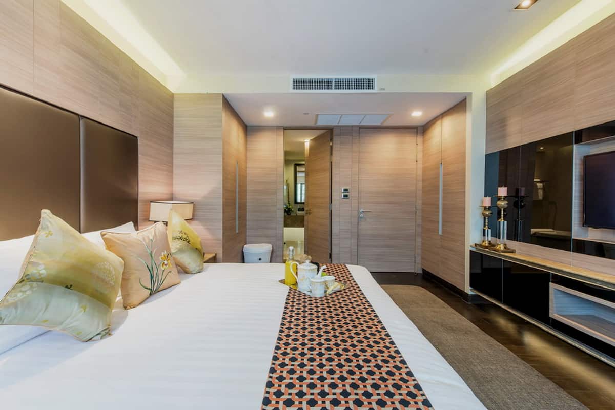 Une chambre d’hôtel moderne, dotée d’un grand lit, d’une télévision et d’une salle de bain visible à travers une porte ouverte.
