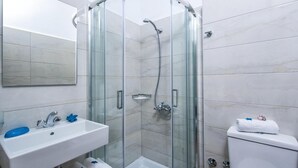 A modern bathroom with a glass-enclosed shower, a white sink, and a toilet. - Floral Hotel (Hersonissos)