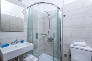 Un baño moderno con ducha de vidrio, lavamanos blanco y retrete.