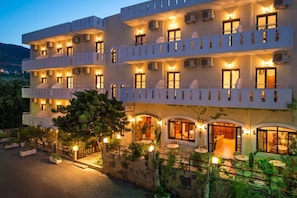 A multi-story hotel with balconies, outdoor seating, and a well-lit entrance. - Floral Hotel (Hersonissos)