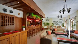 A hotel lobby with a wooden reception desk, a bar area, and a seating area with sofas and tables. - Floral Hotel (Hersonissos)