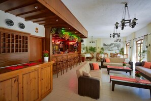 A hotel lobby with a wooden reception desk, a bar area, and a seating area with sofas and tables. - Floral Hotel (Hersonissos)
