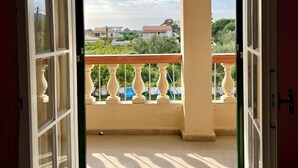 Une porte ouverte donnant sur un balcon d’où l’on peut admirer un quartier résidentiel.