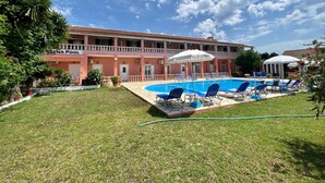 Un hôtel doté d’une piscine, de chaises longues bleues et d’un espace jardin.
