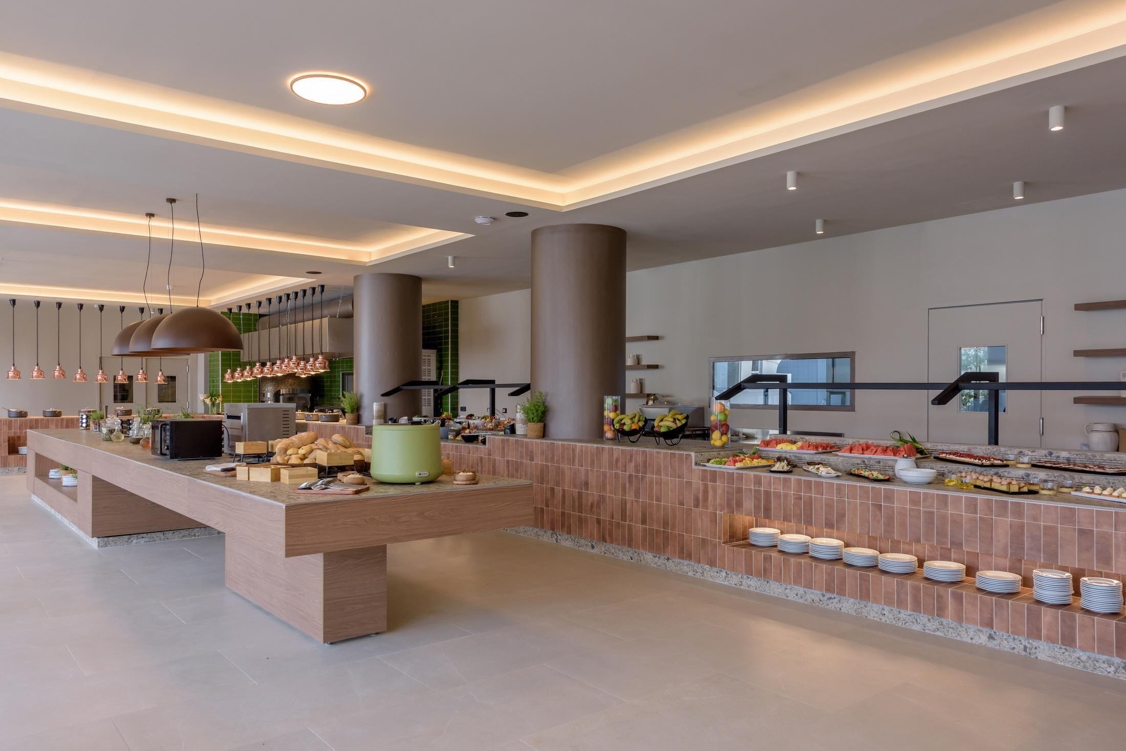 A modern kitchen with a long counter, various appliances, and a buffet area with food and drinks.