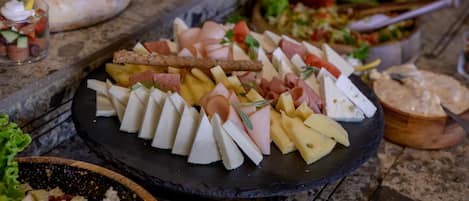 A charcuterie board with various cheeses, meats, and fruits.