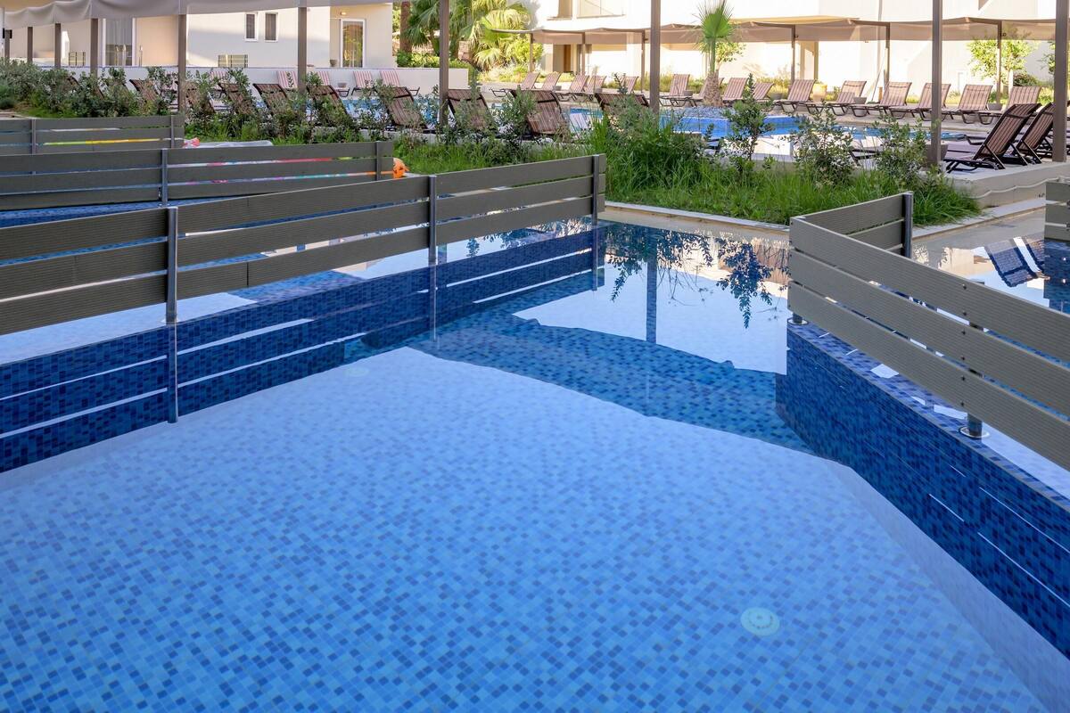 A swimming pool with a tiled deck and lounge chairs.