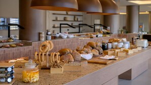 A buffet setup with various breads, pastries, and condiments. - Zeus Hotels YDORIA RESORT - All Inclusive (Rethymno)