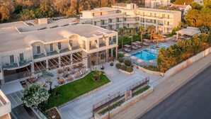 A modern hotel with multiple balconies, outdoor seating, and a swimming pool. - Zeus Hotels YDORIA RESORT - All Inclusive (Rethymno)