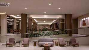 A modern lobby with a central seating area, glass railings, and a staircase leading to upper floors. - Zeus Hotels YDORIA RESORT - All Inclusive (Rethymno)