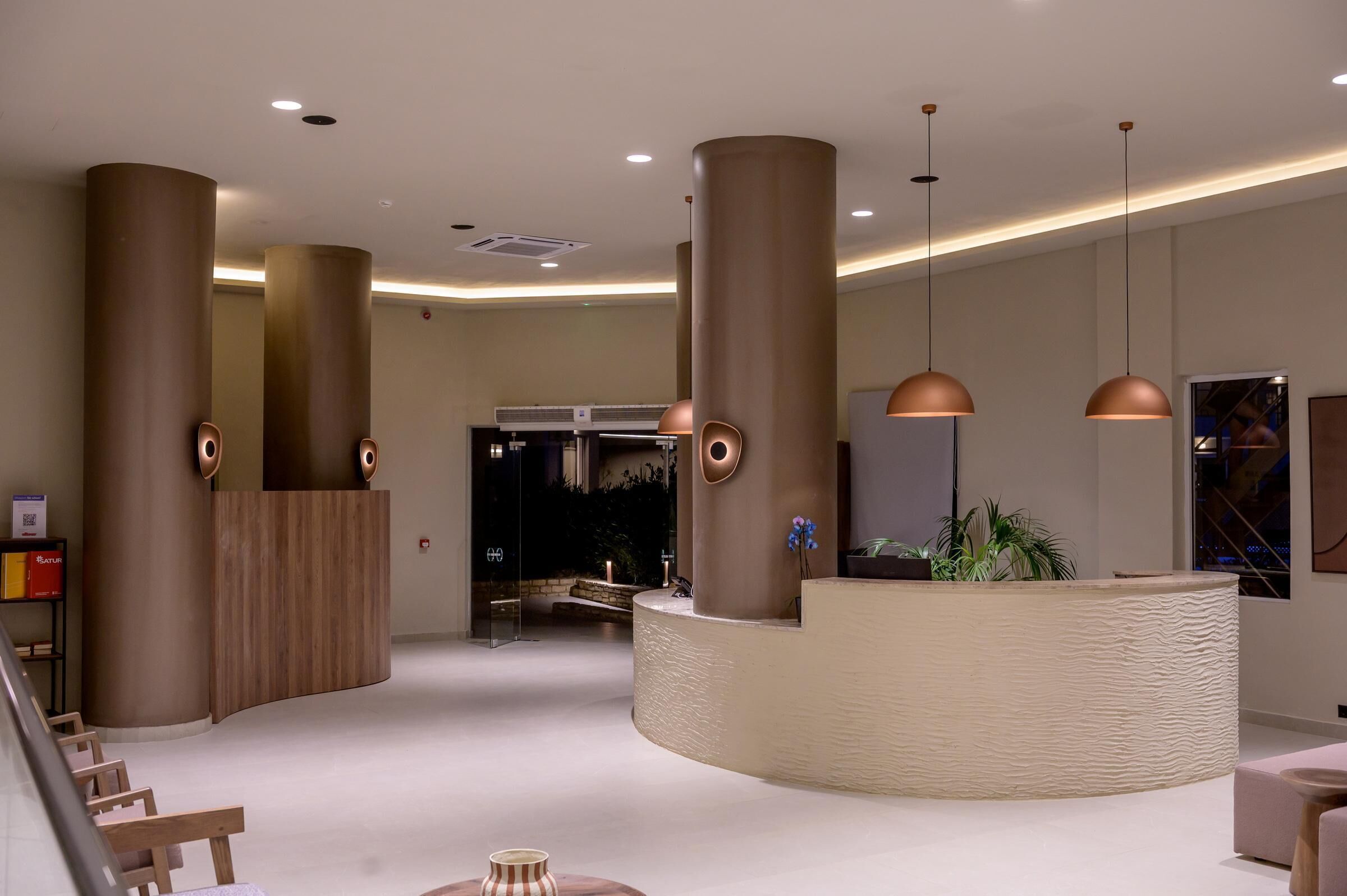 A modern lobby with large cylindrical columns, a reception desk, and pendant lighting.
