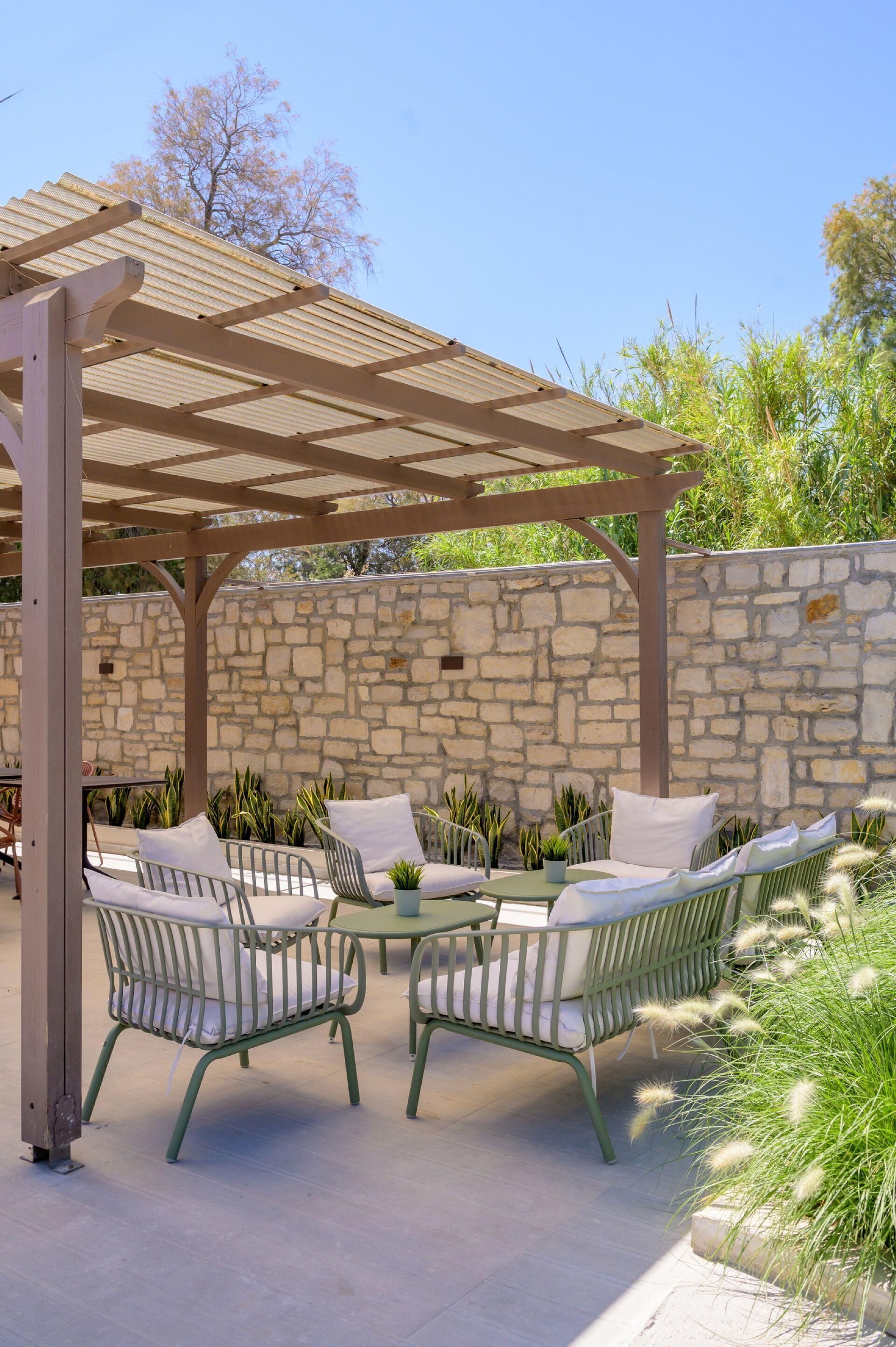A covered outdoor seating area with stone walls and potted plants.