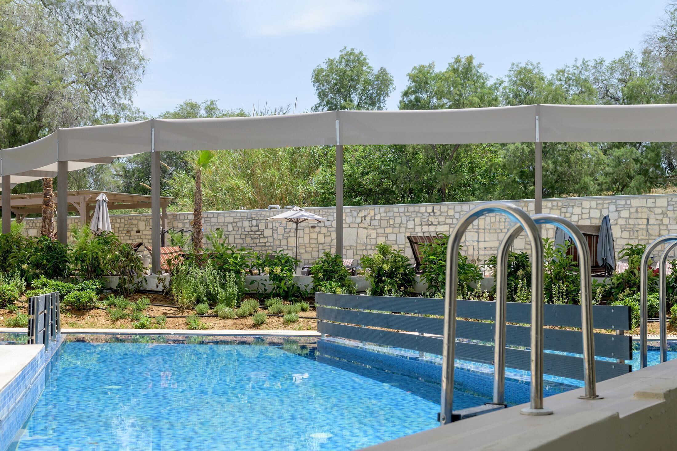 A swimming pool with a stone wall and greenery in the background.