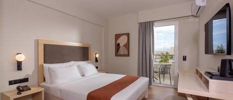 A hotel room with a bed, bedside table with a phone, a desk with a chair, a TV, and a balcony with a view.