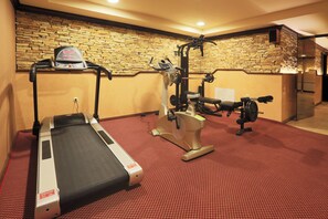 A gym with a treadmill, weight machine, and a bench. - Royal Park Hotel and Apartments (Bansko)