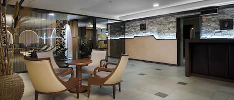 Un vestíbulo con mostrador de recepción, zona de estar con sillas y una pared decorativa.