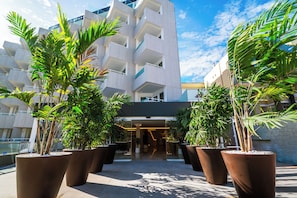 A modern hotel entrance with a geometric facade, large potted plants, and a clear sky. - Hotel HL Sahara Playa (San Bartolomé de Tirajana)