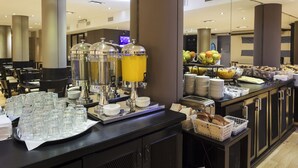 Montaje tipo bufé con varios dispensadores de bebidas, una presentación de frutas y alimentos ordenados.