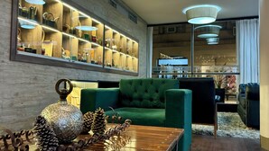 Una sala de estar moderna con un sofá verde, una mesa de centro de madera con objetos decorativos, un aparador empotrado en la pared e iluminación empotrada en el techo.