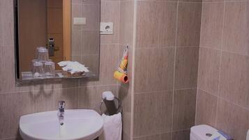 Un baño con lavamanos, espejo, inodoro y toallero.