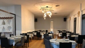 A restaurant with multiple tables and chairs, a central light fixture, and a decorative wall piece. - Las Gondolas Apartments (San Javier)