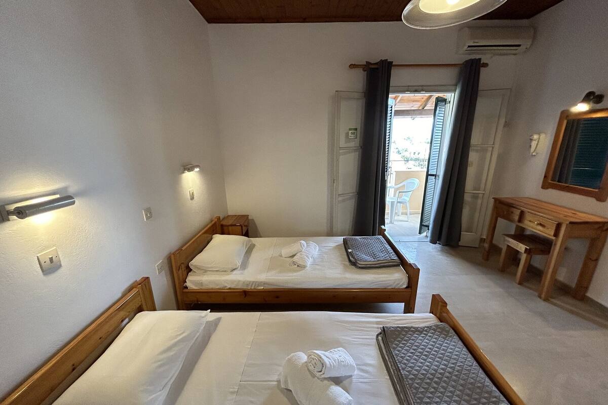 A room with two wooden beds, a small desk, and a mirror.